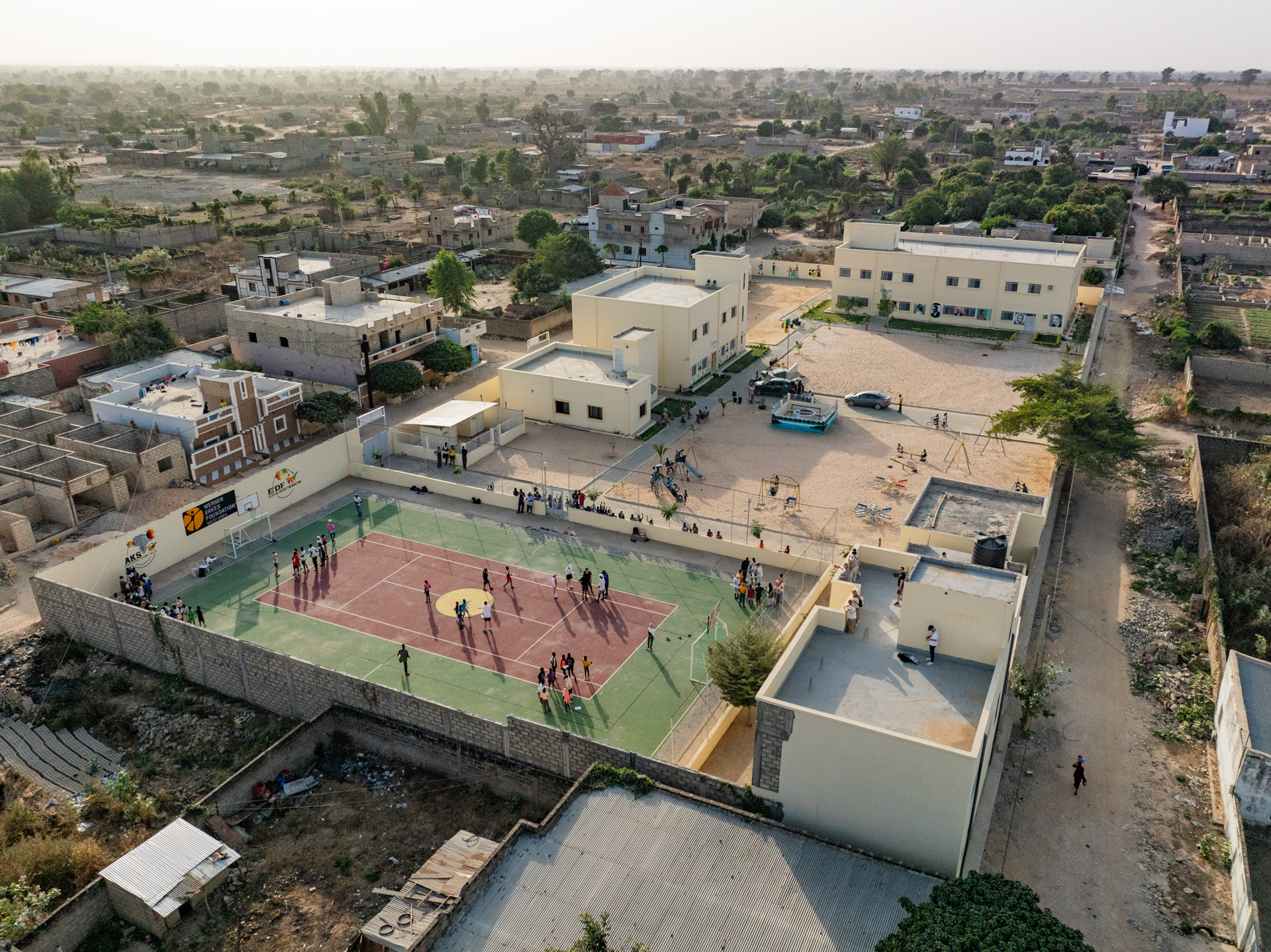 Luftaufnahme von Schulgebäuden, Spielhof und Sportplatz in Kaolack